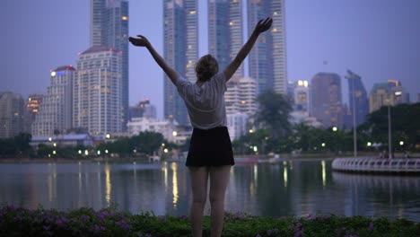 happy woman overlooking bangkok skyline at benjakitti park