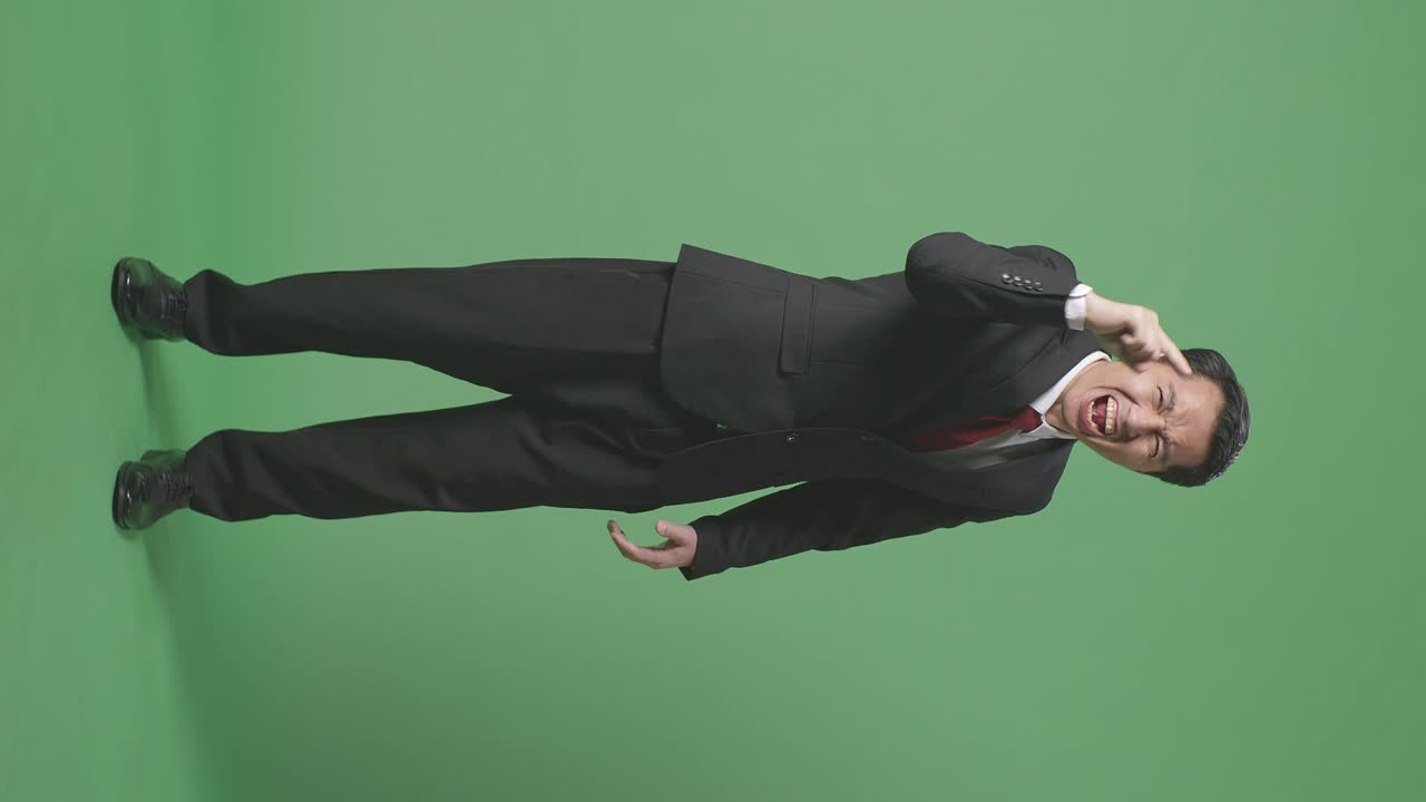 분노 한 아시아 사업가 의 몸 을 가득 채우고 스튜디오 에서 녹색 스크린 에 서 있는 동안 비난