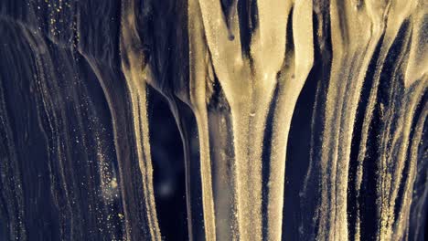 golden ink particles flows in water as colorful chaos on the black background