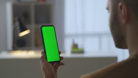 El-Hombre-Sostiene-Un-Teléfono-Inteligente-Moderno-Con-Pantalla-Verde-Para-Tecnología-De-Clave-Cromática-Viendo-Videos-En-Redes-Sociales-Leyendo-Noticias-En-Sitios