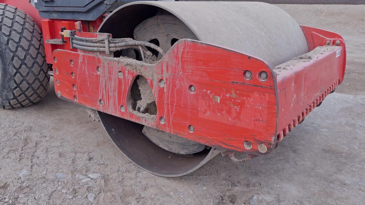 Close-up of road roller compacting dirt at a construction site, showing details of machinery