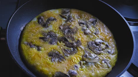 scrambled eggs with sliced mushrooms cooking in a skillet