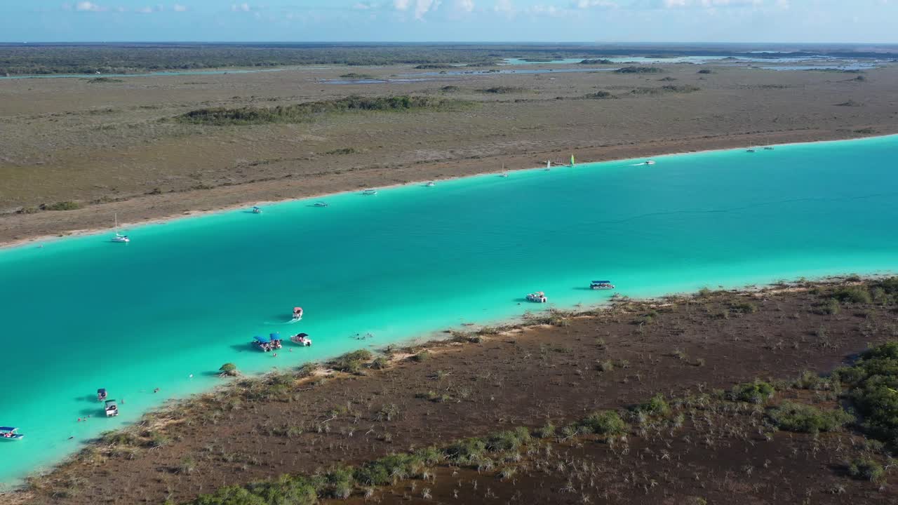 Luftaufnahme von Booten, die in einem türkisfarbenen Lagunenfluss in Bacalar, Mexiko, segeln, mit klarem Wasser und einer malerischen tropischen Landschaft