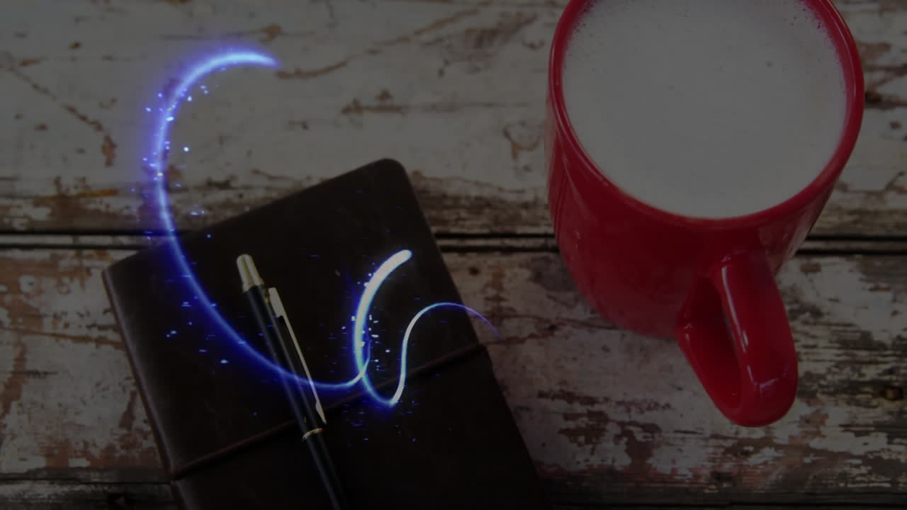 Red ceramic mug being placed on weathered wood desk, showing leather notebook and blue light swirl