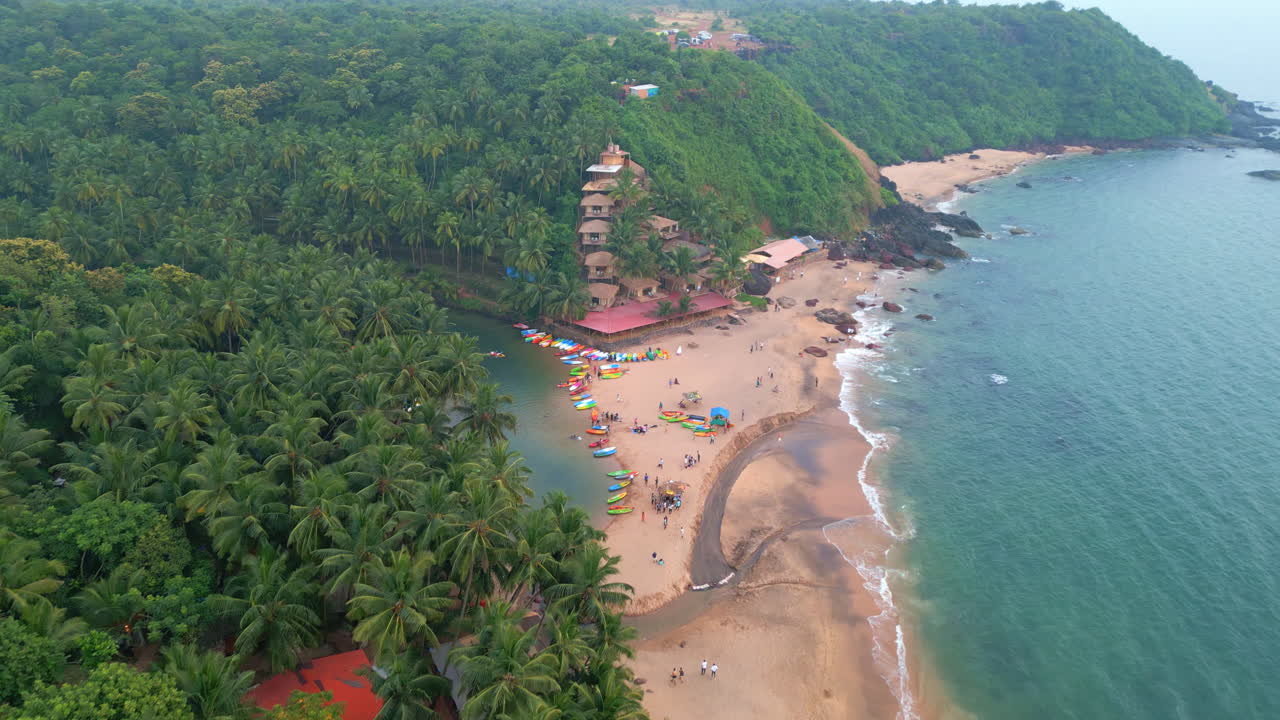 vista superior de la playa de cola con palmeras y coloridos kayaks goa india 4k dron