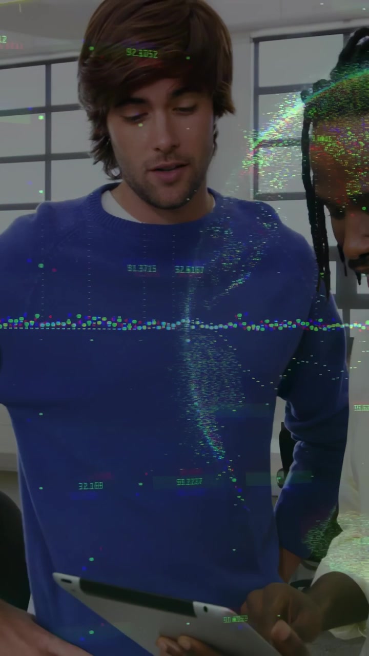Vertical video: Blue-sweater man tapping tablet while peer placing device, working in tech office