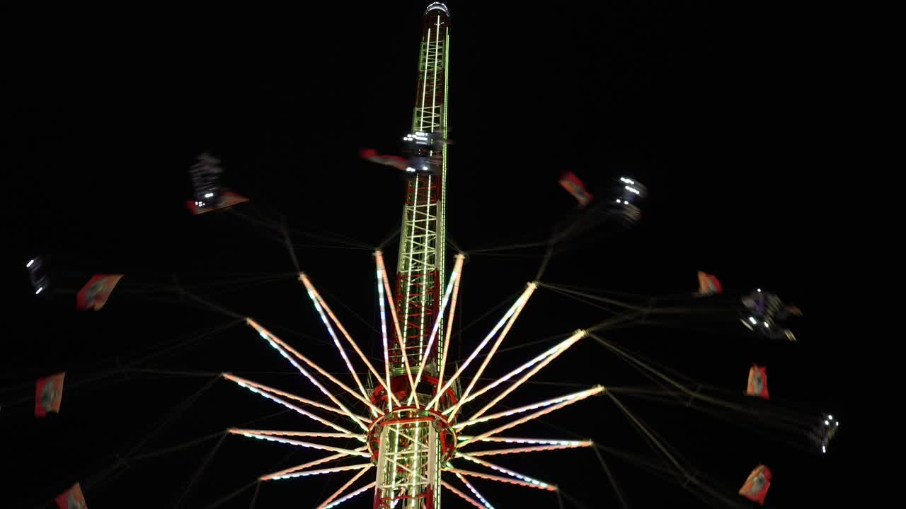 Spinning amusement park ride with lights on dark background