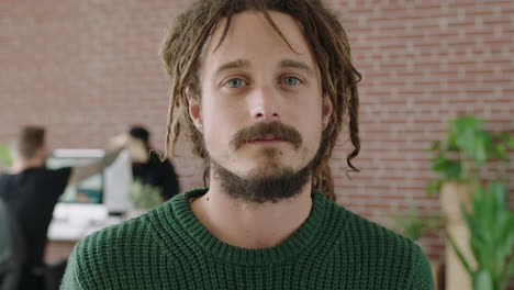 close up portrait of young caucasian man looking serious pensive at camera confident male in startup business workplace dreadlocks hairstyle