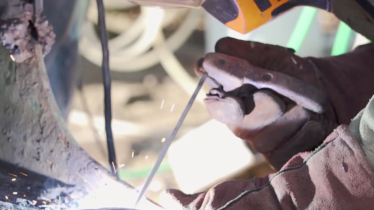 대장장이는 전극이 있는 금속 조각을 용접합니다 - 패닝 다운 슬로우모