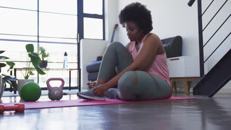 mujer afroamericana de tamaño grande acostada en un tapete de ejercicio haciendo ejercicio