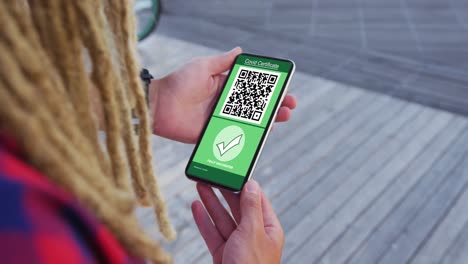 hombre con dreadlocks sosteniendo un teléfono inteligente con certificado de vacunación contra la covid y código qr en la pantalla