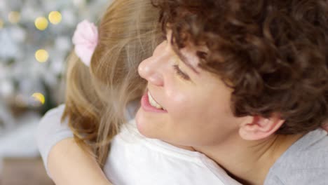 portrait of loving mom and daughter hugging at home on christmas