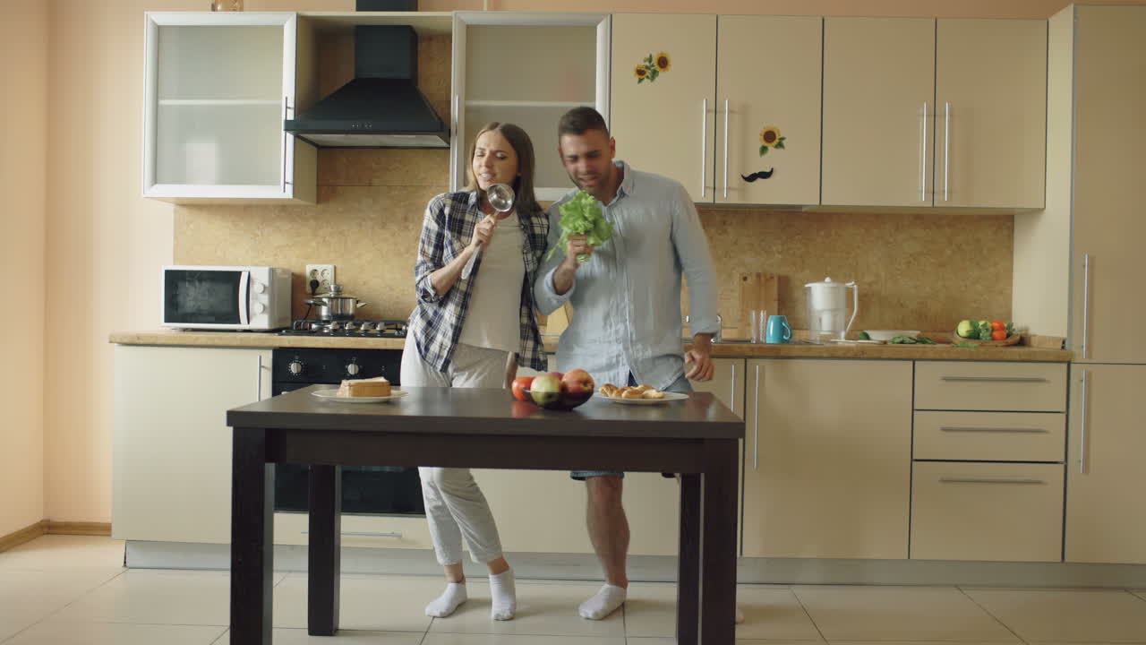 Coppia che canta e balla in cucina