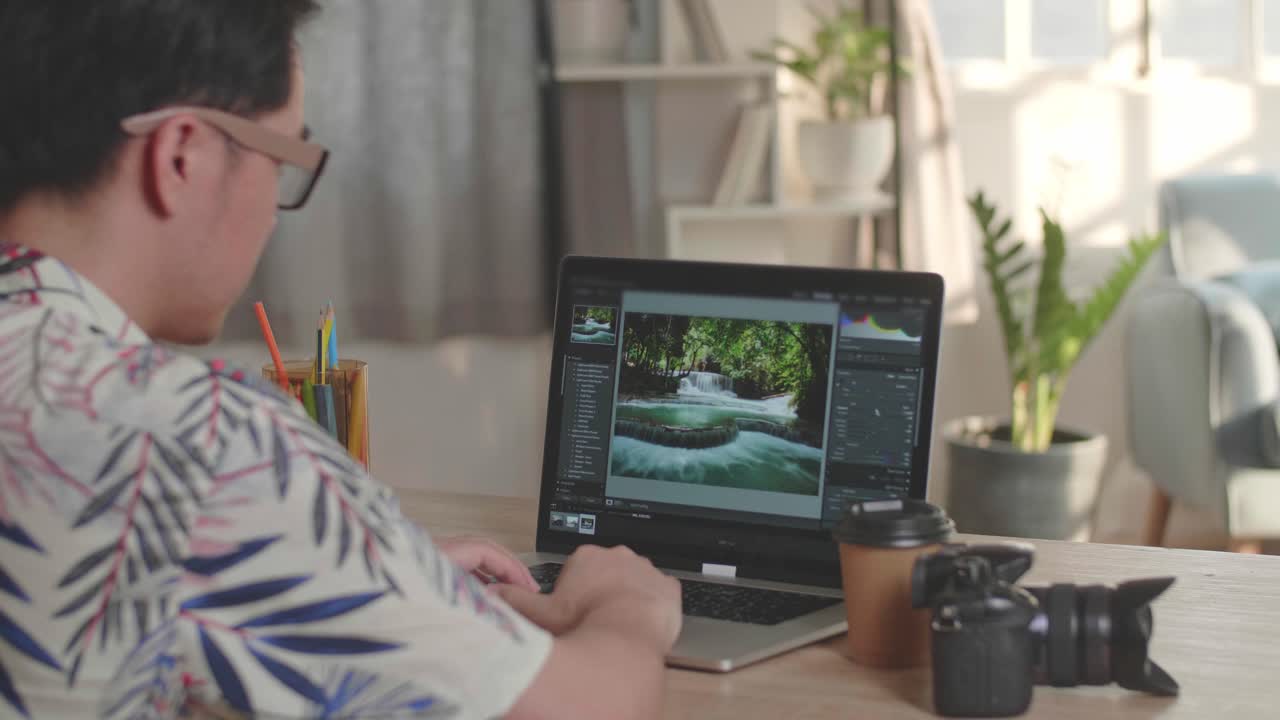 Man Works In Photo Editing App / Software On His Laptop Computer. Photo Editor Retouching Photos Of Beautiful Nature