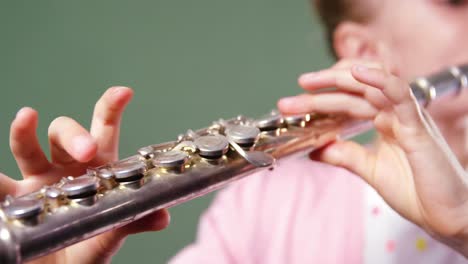 Schoolgirl-playing-flute-in-classroom-at-school