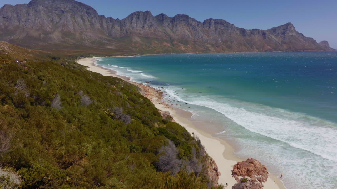 South Africa aerial drone Garden Route Koeel Bay Dappat Se Gat cinematic windy grass surf waves crashing Kogel Bay Beach Cape Town coastline aqua deep blue water Gordon's Bay forward pan up movement