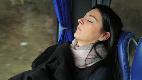 authentic girl sleeping next to bus window. candid real life woman passenger asleep at bus while traveling on road