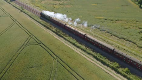 aerial view of a steam engine locomotive train passing on tracks in the countryside in england