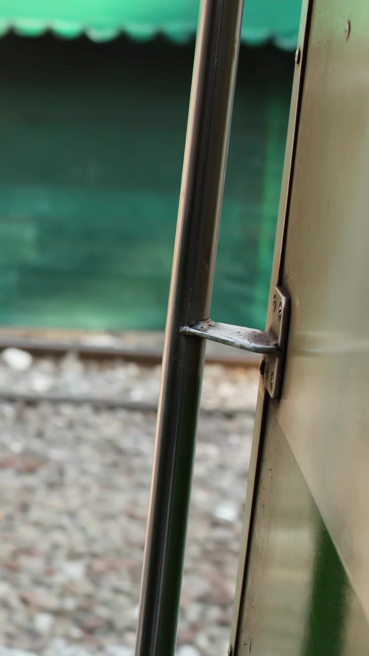 Eine Handaufnahme blickt aus einer offenen Zugtür, während städtische Gebäude und Eisenbahnschienen vorbeiziehen