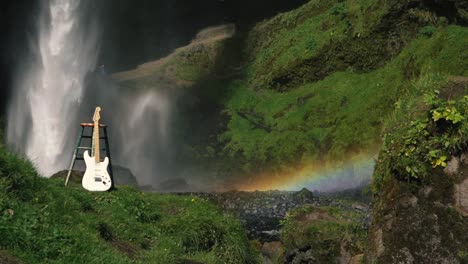 hombre tocando la guitarra frente a una hermosa cascada en islandia-8