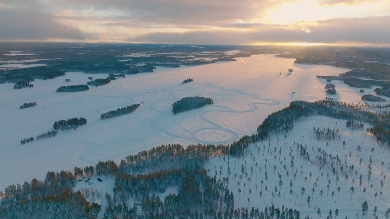 Flygfoto över snötäckt racerbana i Lappland vid polcirkeln med soluppgångshimlen