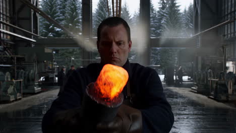 worker holding glowing hot metal in a factory workshop with snowy forest background