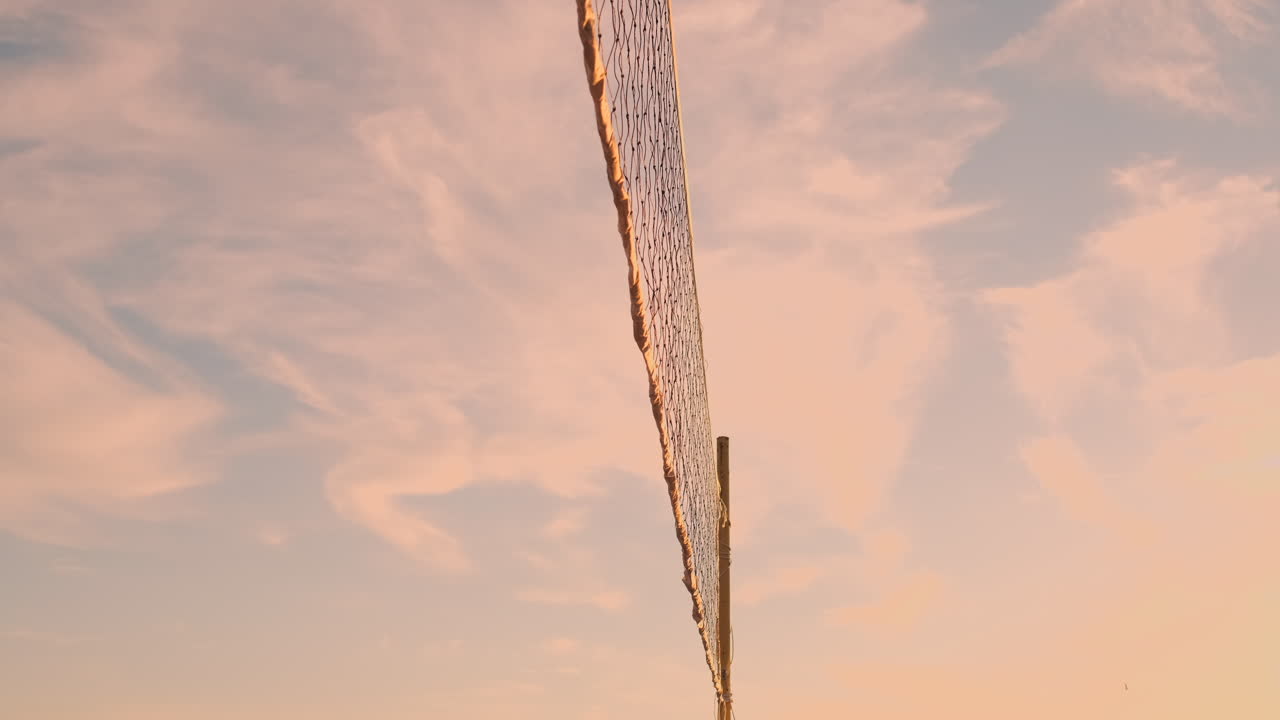 해변 배구 경기 소녀들은 모래에 해가 지는 동안 느린 동작으로 공을 때렸습니다.