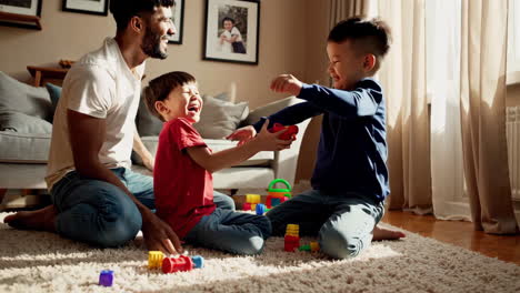 father and sons playing with toys at home
