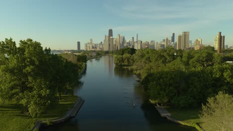 aerial, pan up to reveal chicago skyline with people rowing in lincoln park