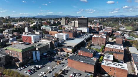 aerial descend shot of lynchburg town in virginia during sunny day. downtown with historic buildings and parking cars on parking lot. wide shot. sunny day with blue sky in october.