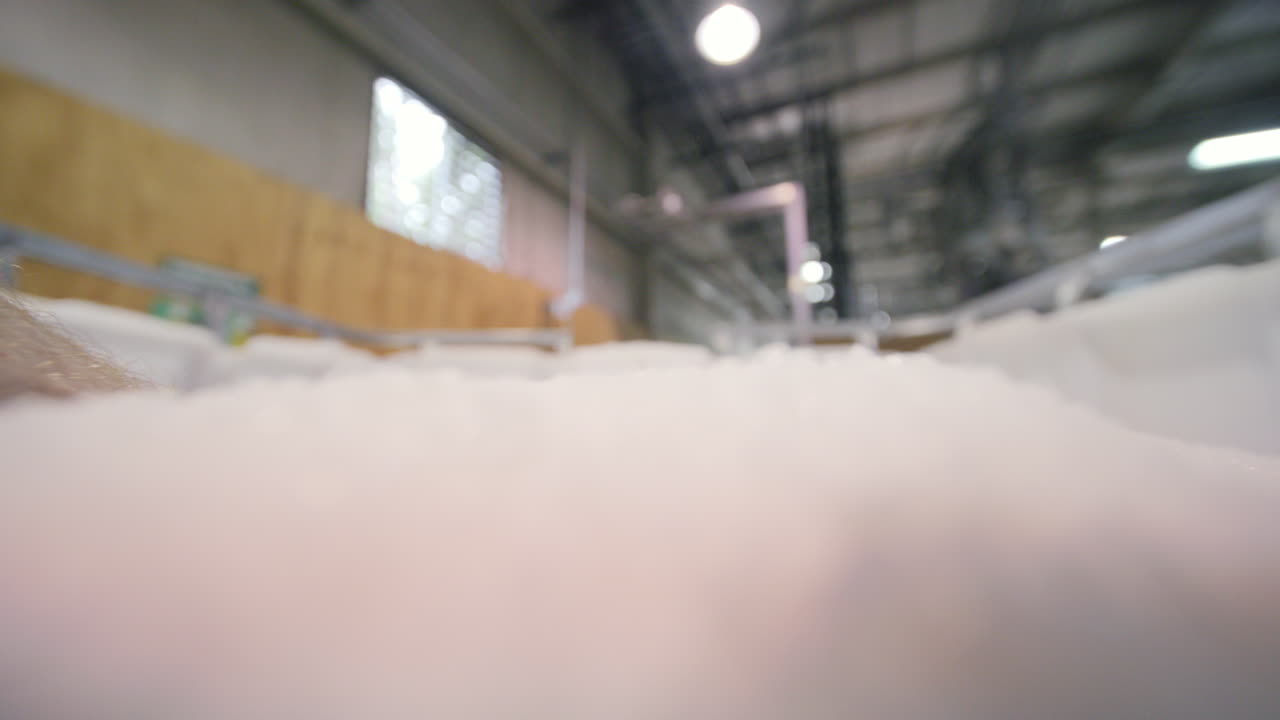 imágenes en cámara lenta de una mano agarrando un puñado de pellets de resina blanca y dejándolos de nuevo en la pila