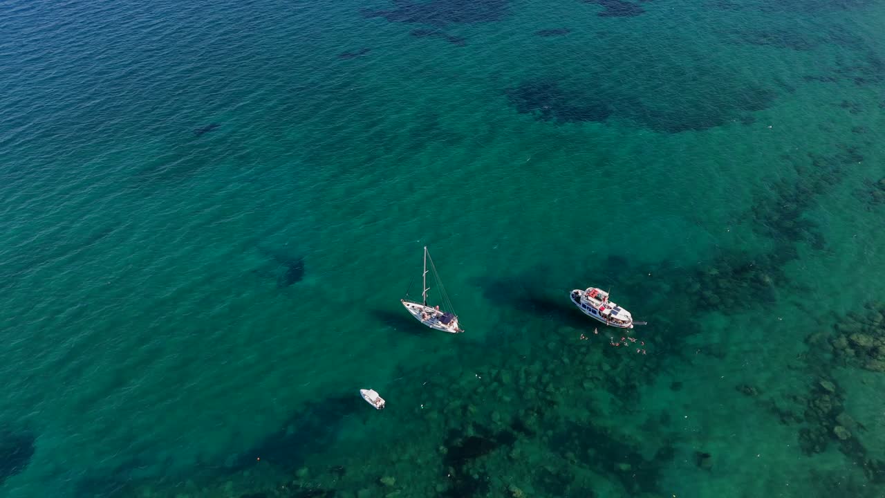 tres barcos turísticos anclados cerca de una playa con aguas turquesas, creta, grecia