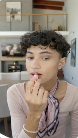 vertical video: young person applying lipstick at home, embracing self-expression and confidence