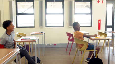multiracial students in classroom chatting and smiling during school group activity