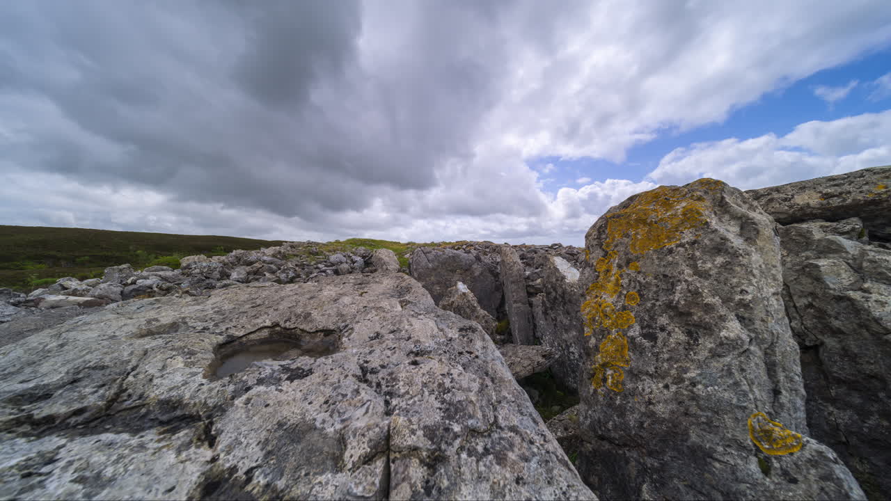 Timelapse af landligt landskab med klippeformation i forgrunden under en solrig, skyet dag set fra Carrowkeel i County Sligo i Irland.