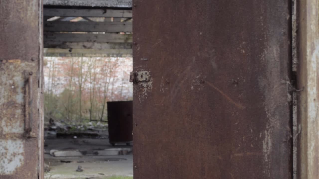 View of empty derelict abandoned building through old rusty doors