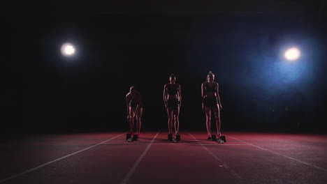 female runners at athletics track crouching at the starting blocks before a race. in slow motion.