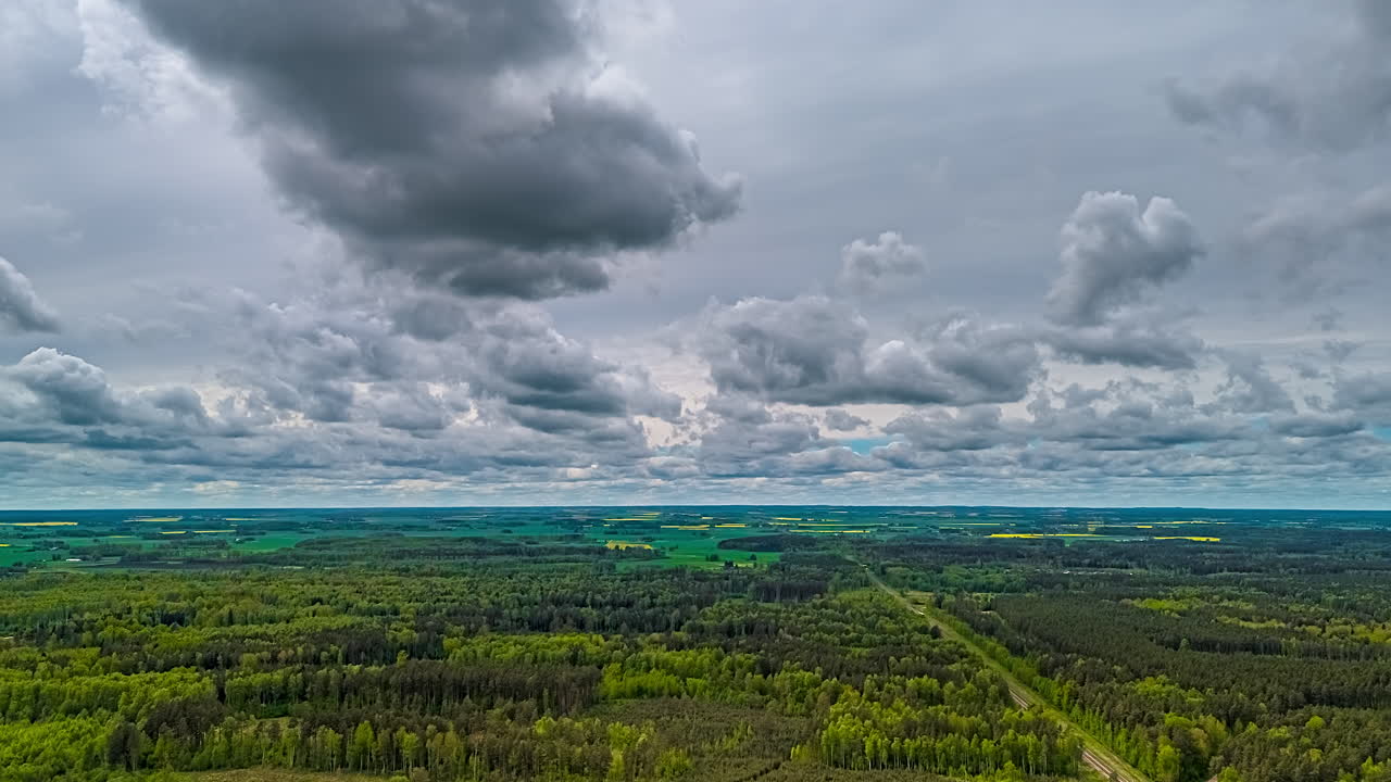 Moving clouds above forest landscape in aerial timelapse