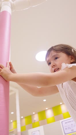 energetic young girl runs and pushes soft padded attraction in indoor play center, enjoying active fun and movement