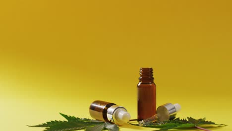 Video-of-marijuana-leaves-and-bottle-of-cbd-extract-on-yellow-background