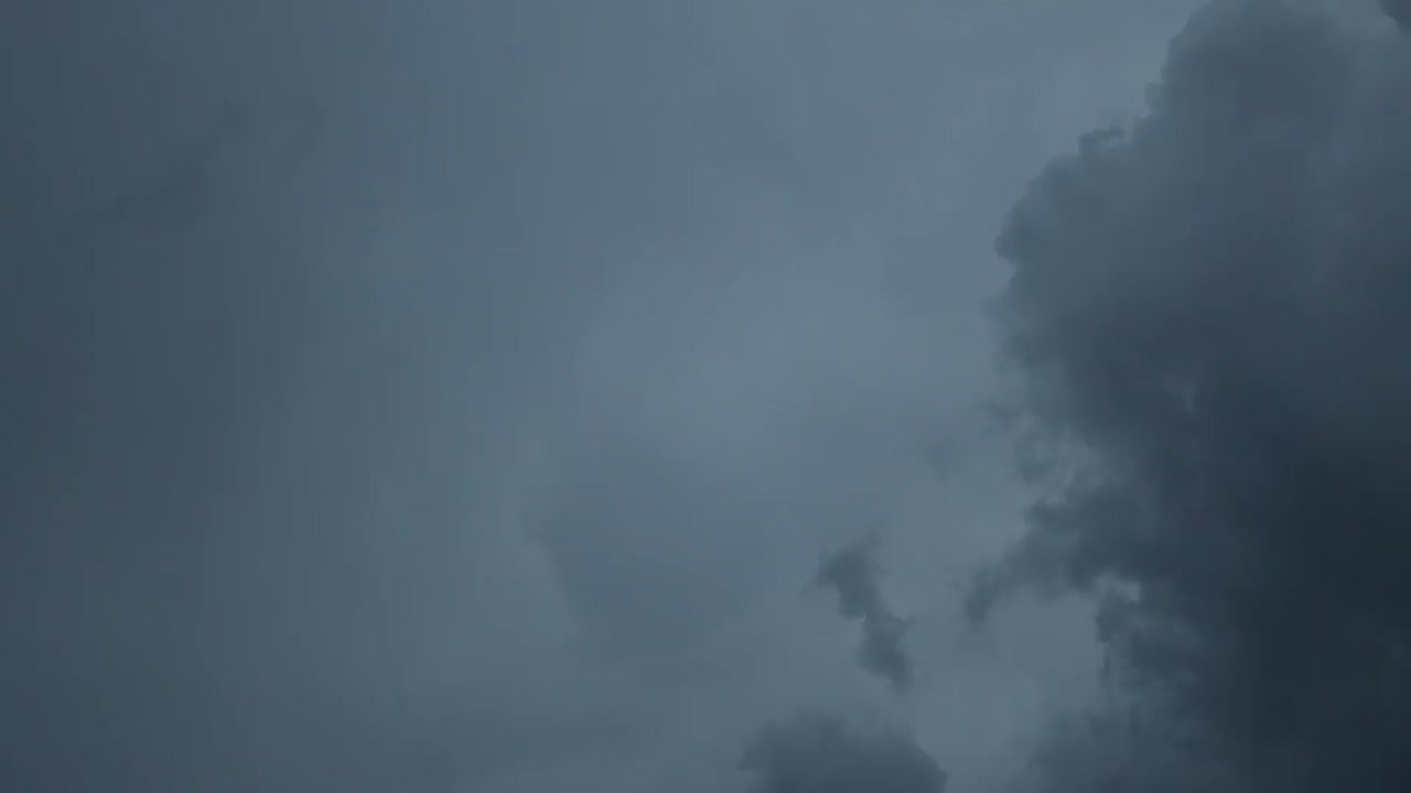 Dramatic dark storm clouds fill the sky, creating a moody, overcast atmosphere with varying shades of gray and subtle light breaking through