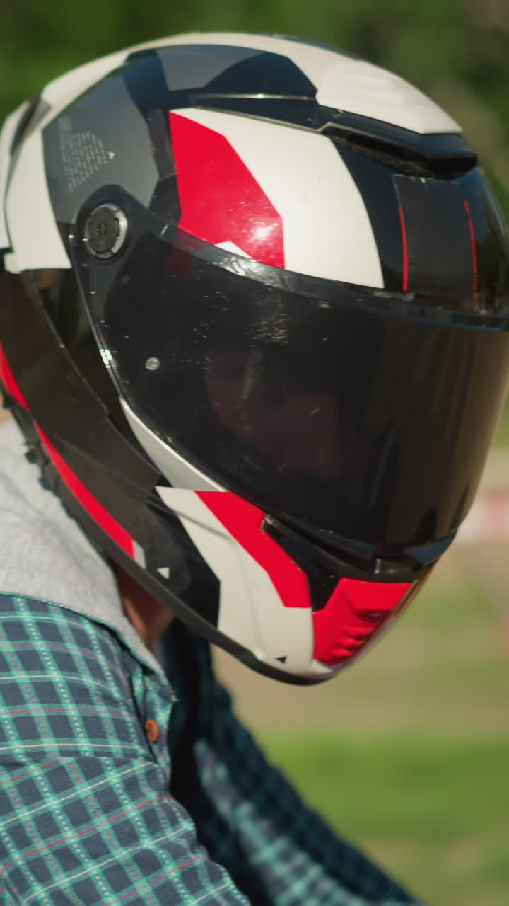 dos amigos montan una bicicleta eléctrica con cascos mientras miran la cámara, el fondo está borroso, con una cinta de advertencia y coches estacionados