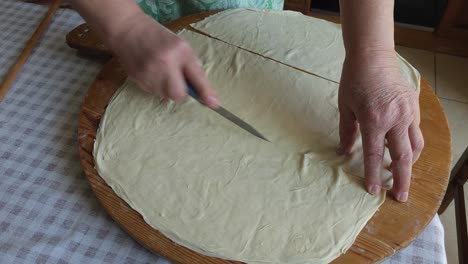 knife in hand, layering the dough, traditional pie ready for baking - balkans culinary art in motion