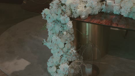 close up of a wedding decor table with cascading white flower arrangement and candle lanterns