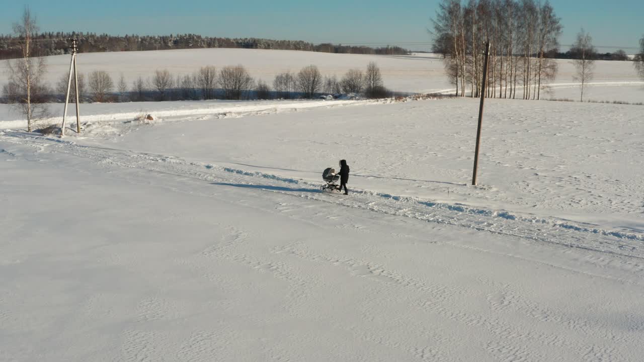 madre soltera caminando por un camino de campo con un cochecito, paisaje de invierno