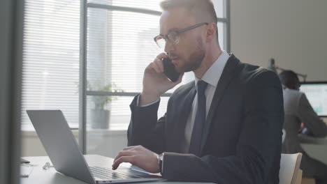 businessman talking on phone and using laptop in office