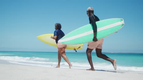 senior couple running with surfboards