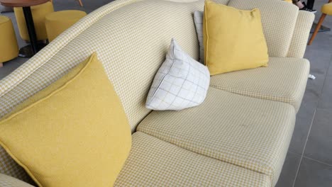sofá de cuadros amarillo y beige con cojines en un café