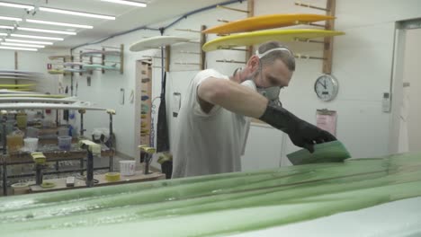 slow motion surfboard being glassed and painted with squeegee