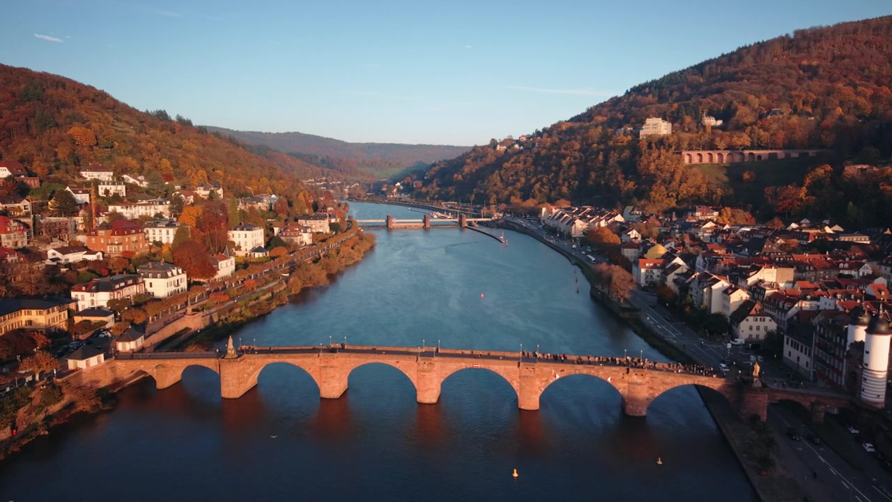 Avvicinamento dinamico con drone al Ponte Vecchio e alla Porta del Ponte di Heidelberg nella luce dorata della sera.